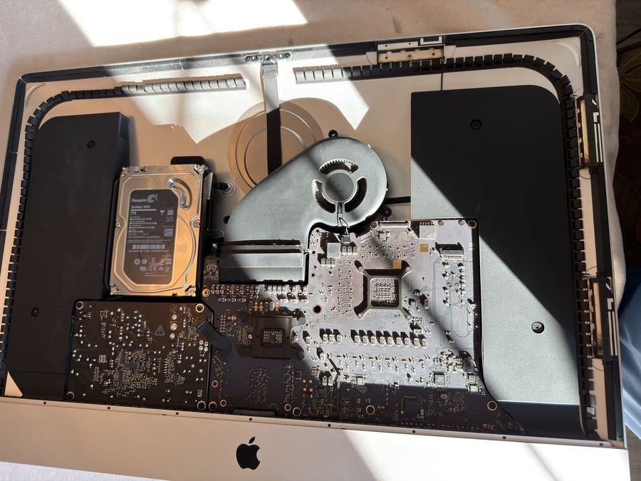 iMac with the display panel removed, showing the hard drive, fan, logic board and power supply still installed