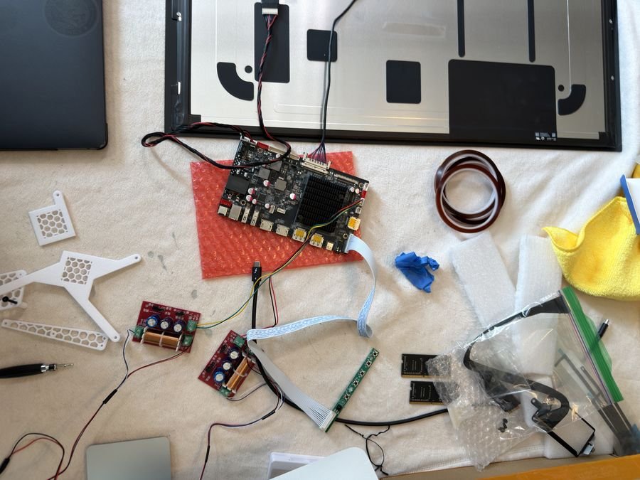 Bench layout: bare 5K panel, R1820 driver board, crossover boards, 3D printed brackets and cables laid out on a work surface
